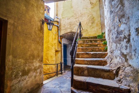 Narrow passage with staircases among medieval houses in old Gandria village, Switzerland