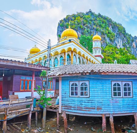 Las cúpulas doradas de la mezquita detrás de las casas de piedra de madera de la aldea flotante de Ko Panyi, bahía de Phang Nga, Tailandia