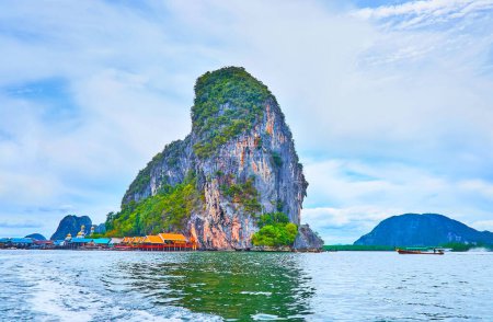 The scenic landscape of Ko Panyi Island and colored roofs of floating village, located at the rock's foot, Phang Nga Bay, Thailand