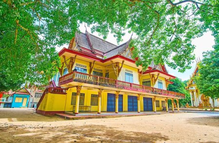 El patio verde del templo de la cueva de Wat Suwan Kuha con árboles extendidos altos y edificios monásticos, Phang Nga, Tailandia