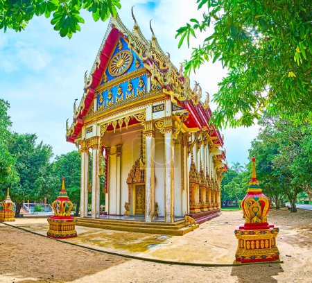 Der atemberaubende Ubosot des Wat Suwan Kuha Tempels mit geschnitzten und geschnitzten Dekoren, einem übermüdeten Dach und vergoldeten hölzernen Barrikaden mit Naga-Schlangen, Phang Nga, Thailand