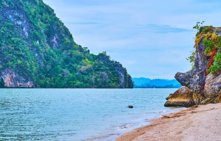 The rocky Ko Raya Ring Island, covered with tropic vegetation is seen from the sand coast of James Bond Island, Phang Nga Bay, Thailand