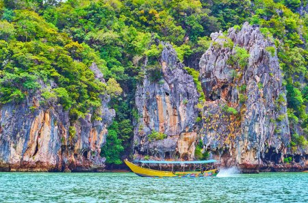 Das farbige Touristenboot vor dem Ko Ta Pu Felsen und der Küste der James Bond Insel, Phang Nga Bay, Thailand