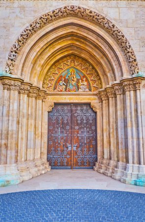 Das geschnitzte steinerne Eingangstor der Matthias-Kirche, verziert mit Wandsäulen und der Statue der Jungfrau Maria und der Engel, Budapest, Ungarn