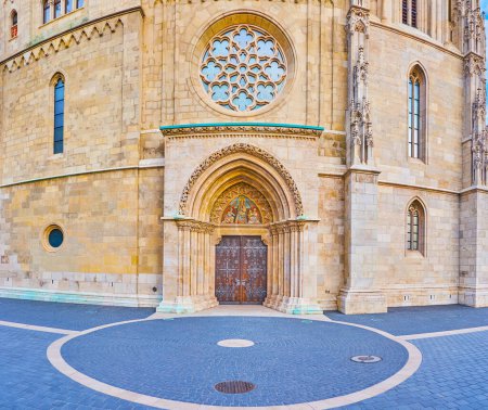 Das Rosettenfenster und das geschnitzte Bogentor der Matthias-Kirche, geschmückt mit der Statue der Jungfrau Maria und Engeln über der Tür, Budapest, Ungarn