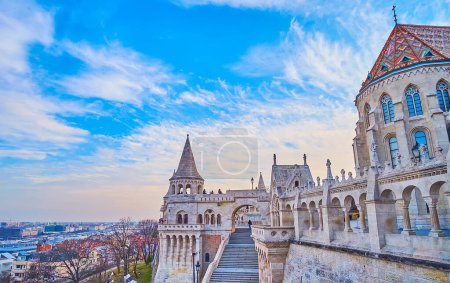 Las paredes de piedra tallada, galerías y torres del Bastión del Pescador con ábside de la Iglesia de Matías en el fondo, Budapest, Hungría