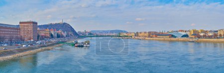 Panorama of bright blue Danube River with Budapest University campus, Gellert Hill and Balna on its banks, Budapest, Hungary
