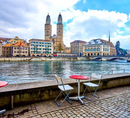 Restaurant's outdoor seating on the Wuhre promenade with view on Grossmunster church, Zurich, Switzerland