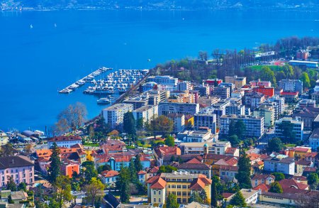 Der Blick von oben auf die Dächer der Stadt, den Lago Maggiore und den kleinen Hafen mit festgemachten Yachten, Locarno, Tessin, Schweiz