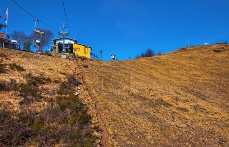 The dried up yellow slope and upper station of the chair lift atop Mount Cimetta, Ticino, Switzerland