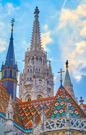 Der steinerne gotische Glockenturm, kleinere Türme und das verzierte Dach der Matthias-Kirche, mit traditionellen Zsolnay-Ziegeln verkleidet, Budapest, Ungarn