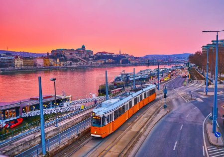 Photo for Jane Haining embankment with vintage tram, Danube with moored ferries and Buda Castle at beautiful purple twilight, Budapest, Hungary - Royalty Free Image