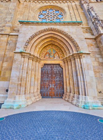 Das mittelalterliche Steintor der Matthias-Kirche mit Holztür, geschmückt mit Mustern und Fresken über dem Eingang, Budapest, Ungarn