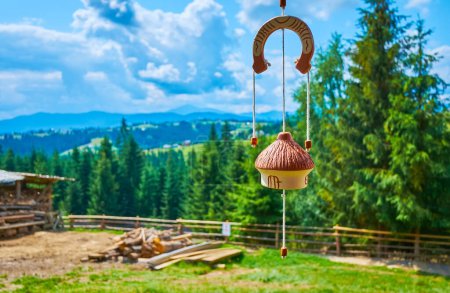 The clay house-bell with horseshoe souvenir against the conifer forest, Mountain Valley Peppers handicraft village, Ukraine