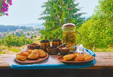 The tray with homemade pancakes and herbal tea on the terrace of the house in mountain forest, Carpathians, Ukraine