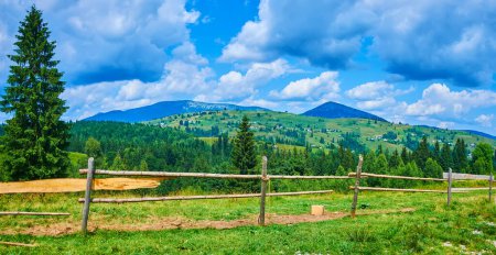 Green mountains, covered with meadows and conifer forests, behind the fence, Yablunytsya, Carpathians, Ukraine