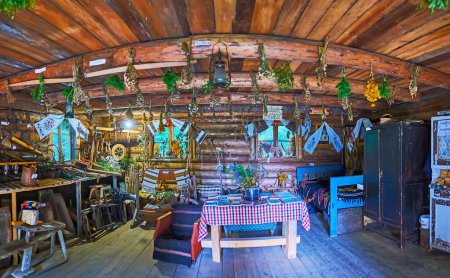 Téléchargez les photos : YABLUNYTSYA, UKRAINE - 24 JUILLET 2021 : Intérieur de la maison de Hutsul molfar (sorcier folklorique) avec des meubles en bois, des herbes, des ustensiles de cuisine et des serviettes décoratives rushnyk dans le village artisanal Mountain Valley Peppers (Polonyna Pertsi), le 24 juillet à Yablunytsya - en image libre de droit