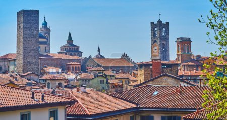 The medieval skyline of Bergamo Citta Alta with red tile roofs and carved stone towers of churches and palaces, Italy