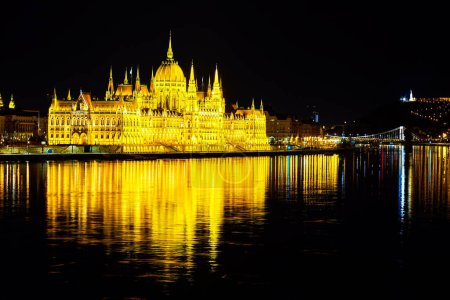 Bright illuminated Parliament building on bank of Danube River, Budapest, Hungary