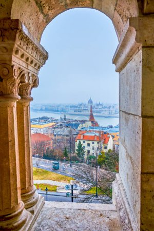 La vue à travers les fenêtres de l'arcade au Bastion des Pêcheurs, mettant en valeur le Parlement, les maisons et le Danube à Budapest, Hongrie.