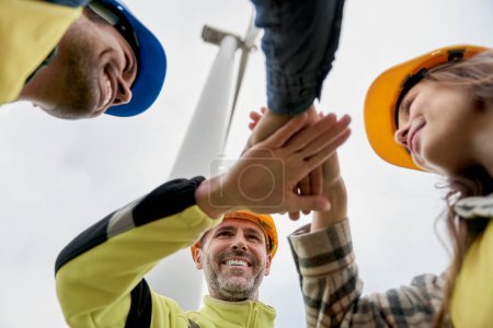 Photo for Low angle view of team of  engineers bringing hands together after work on wind turbine field - Royalty Free Image