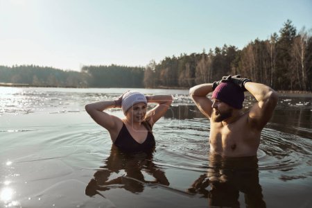Foto de Caucásico pareja de pie en congelado lago con las manos levantadas - Imagen libre de derechos