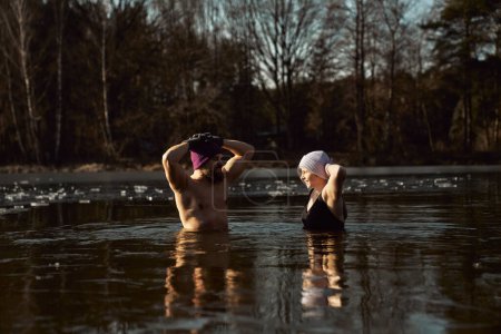 Foto de Caucásico pareja de pie y hablando en congelado lago con las manos levantadas - Imagen libre de derechos