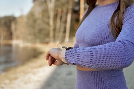 Foto de Caucásico joven mujer comprobar los parámetros en el smartwatch estar al aire libre en el invierno - Imagen libre de derechos