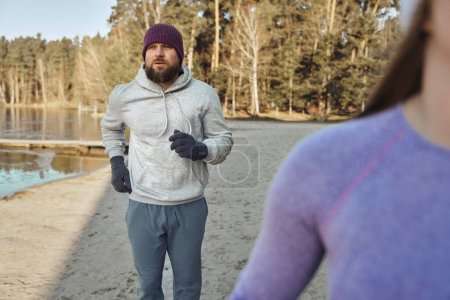 Photo for Adult caucasian couple jogging on beach by the lake in the winter - Royalty Free Image