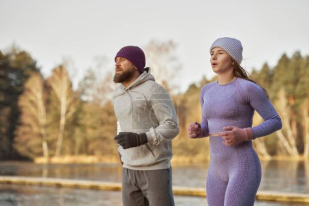 Photo for Adult caucasian couple running outdoors in the winter by the lake - Royalty Free Image