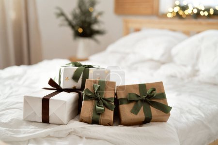 Téléchargez les photos : Pile de cadeau de Noël avec ruban vert couché sur le lit - en image libre de droit
