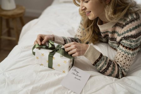 Téléchargez les photos : Femme caucasienne enveloppant cadeau de Noël et carte de voeux couché à côté - en image libre de droit