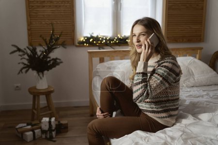 Photo for Wide shot caucasian woman calling while sitting on bed - Royalty Free Image