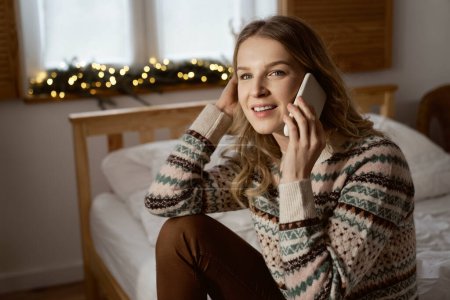 Photo for Caucasian woman calling while sitting on bed - Royalty Free Image