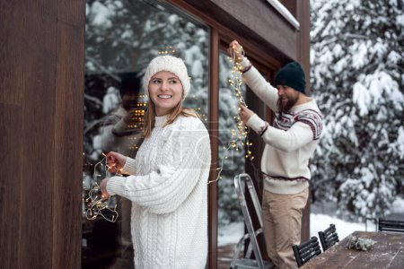 Foto de Caucasian couple decorating home for Christmas in lights - Imagen libre de derechos