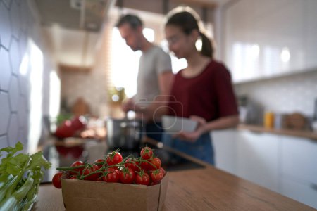 Photo for Close up of cherry tomatoes in the kitchen with family in background which cooking together - Royalty Free Image