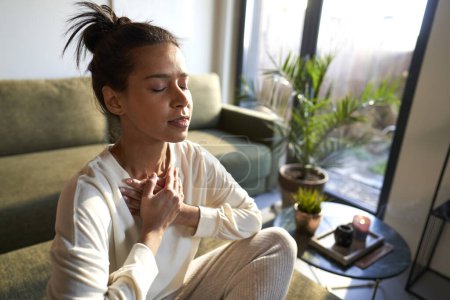 Téléchargez les photos : Mixed race woman meditating at home with eyes closed - en image libre de droit