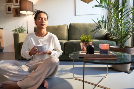 Photo for Mixed race woman enjoying the peace at home with cup of coffee - Royalty Free Image