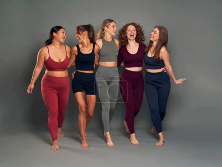 Foto de Full length of group of five young women in sports clothes having fun in studio shot - Imagen libre de derechos