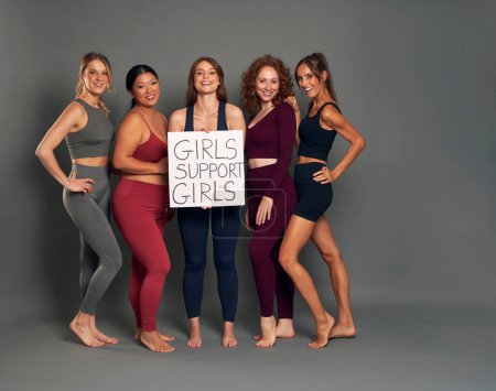 Foto de Cinco mujeres con ropa deportiva en el estudio dispararon con una pancarta - Imagen libre de derechos