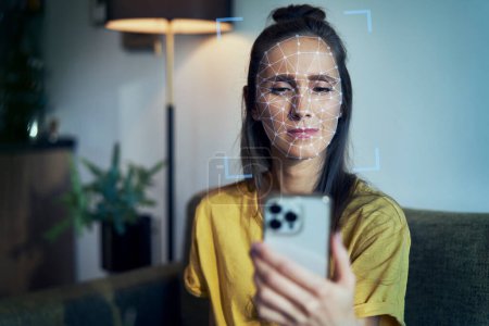 Téléchargez les photos : Jeune femme utilisant le téléphone avec reconnaissance faciale - en image libre de droit