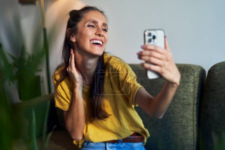 Photo for Young woman having video call at home using mobile phone - Royalty Free Image