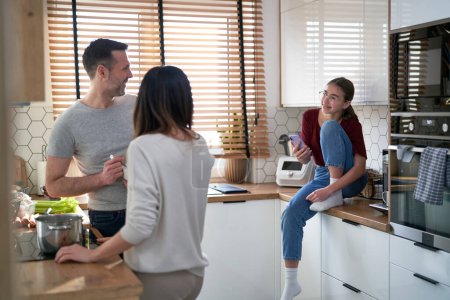 Photo for Caucasian teenager girl talking with patents in kitchen - Royalty Free Image