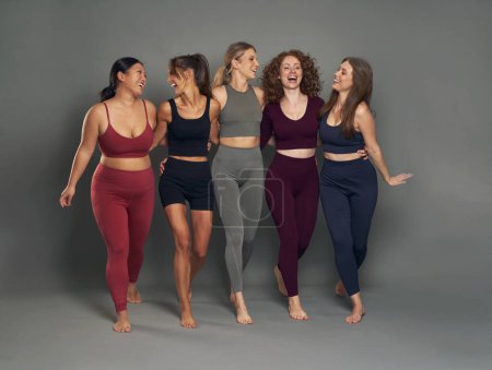 Foto de Longitud completa de grupo de cinco mujeres jóvenes en ropa deportiva que se divierten en la toma de estudio - Imagen libre de derechos