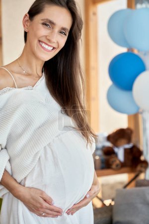 Foto de Retrato de mujer embarazada sonriente con decoraciones azules al aire libre - Imagen libre de derechos