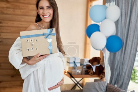 Photo for Portrait of smiling pregnant woman with blue gift for baby shower - Royalty Free Image