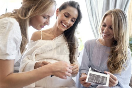 Téléchargez les photos : Group of female friends looking an ultrasound scan result - en image libre de droit