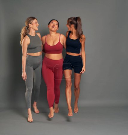 Foto de Longitud completa de tres mujeres jóvenes en ropa deportiva caminando en el estudio de tiro - Imagen libre de derechos