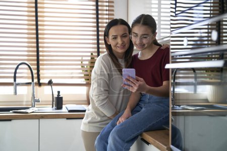 Photo for Caucasian mom with teenager daughter looking at mobile phone - Royalty Free Image