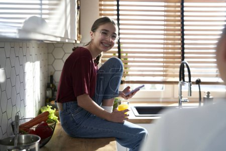 Photo for Caucasian teenager talking with mom and sitting in the kitchen - Royalty Free Image